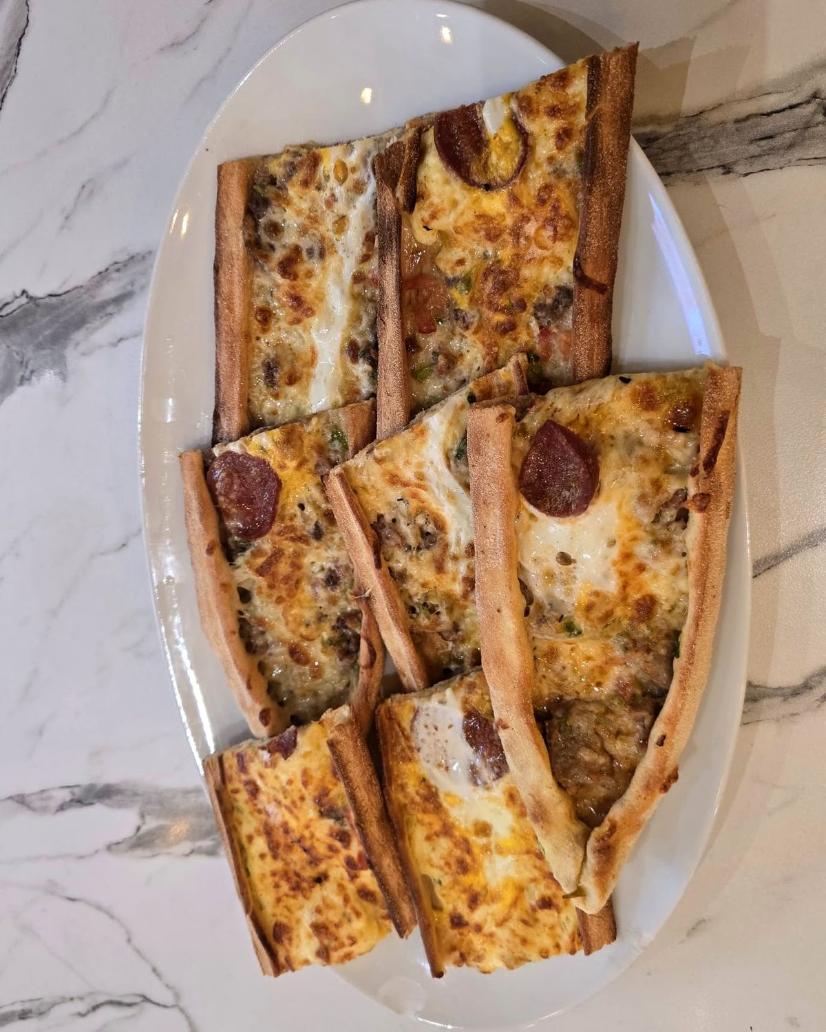 Şefin pidesi coupé en lanières, avec sucuk et fromage fondu